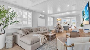 A modern living room with a sectional sofa, a dining area, and a kitchen in the background.