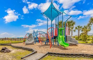 Ein Spielplatz mit Klettergerüsten, einer Rutsche und einer Schaukel.