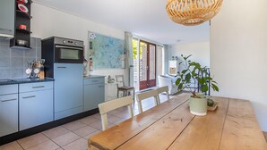Een moderne keuken met grijze kastjes, een houten eettafel en een hanglamp.
