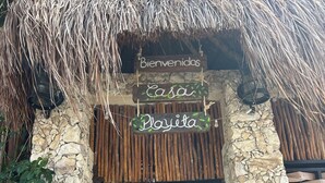 A rustic entrance with a thatched roof, stone walls, and wooden slats.