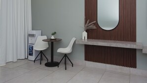 A small room with a white table, two white chairs, a small white plant, a mirror, and a vending machine. - Apartamento Santa Rita #5 cerca de restaurantes (Danlí)