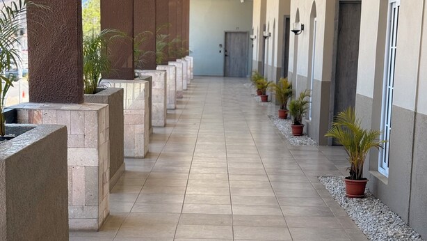 A covered corridor with tiled flooring, stone pillars, potted plants, and a view of the mountains in the background. - Apartamento Santa Rita #5 cerca de restaurantes (Danlí)
