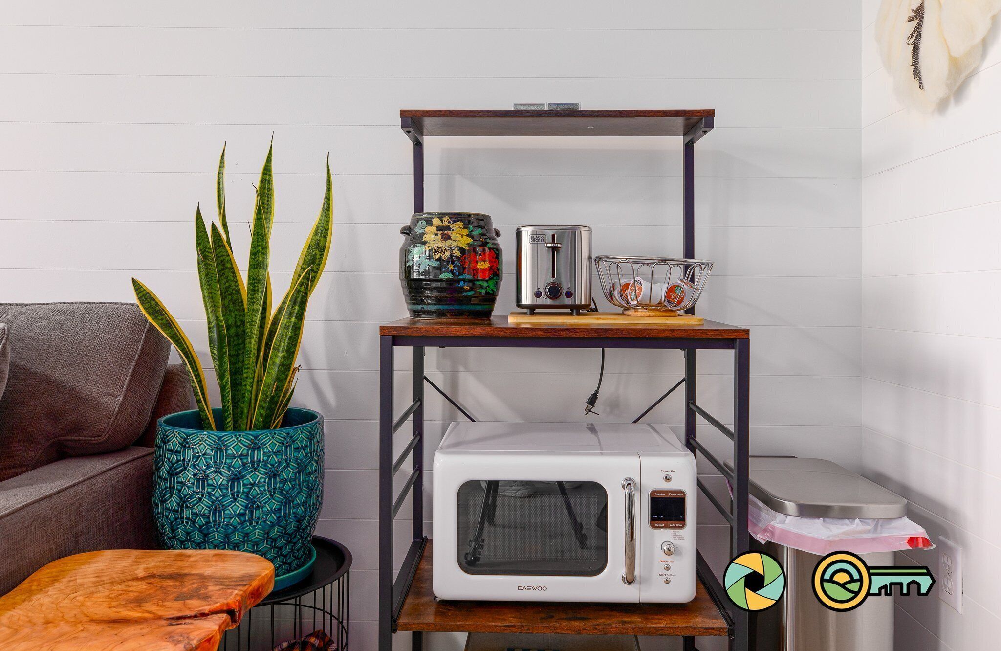 Een keuken met een magnetron, broodrooster en een plank met een decoratieve vaas en een plant.