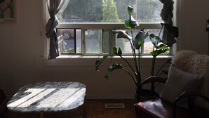 A room with a large window, a table, a chair, and a potted plant.