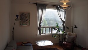 A living room with a sofa, a small table, a potted plant, and a chair.