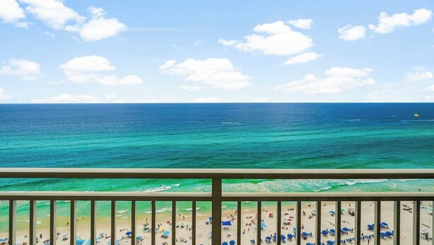 Blick auf den Strand vom Balkon mit Geländer, Meer und blauem Himmel.