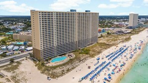 Ein Hochhaus-Hotel mit Pool, Strandlage und zahlreichen Sonnenschirmen.