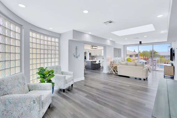 A spacious living area with a modern kitchen, large windows, and a view of the outdoors.
