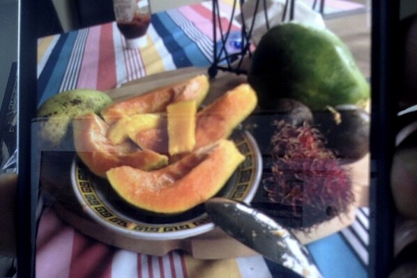 A table with a plate of sliced fruits and a knife.