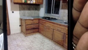 Une petite cuisine avec des meubles en bois, une cuisinière à gaz et des carreaux de sol à motifs.