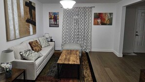 Un salon avec un canapé blanc, une table basse en bois et un rideau à motifs.