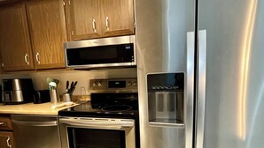 Une cuisine équipée d’appareils électroménagers en acier inoxydable, notamment un réfrigérateur, un four et un four à micro-ondes.