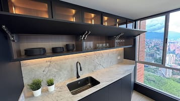 Eine moderne Küche mit integriertem Spülbecken, dunklen Schränken und Blick auf eine Stadtlandschaft durch große Fenster.