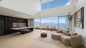 Una cocina moderna con una isla central, un comedor con vistas y un espacio de sala con sofá y reposapiés.