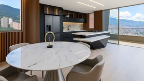 Cocina moderna con una isla de mármol, muebles negros y vista a la ciudad.