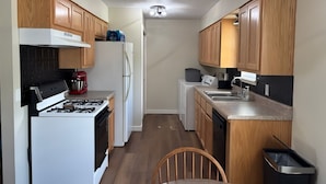 A compact kitchen with wooden cabinets, a white stove, a refrigerator, and a sink.