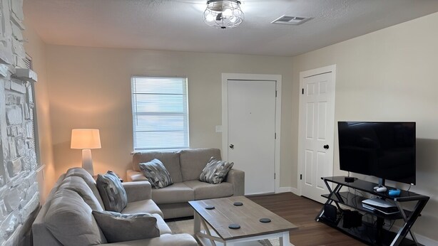 A living room with a sofa set, a coffee table, a TV, and a gaming console.