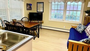 A kitchen with a sink, dining table, chairs, and a TV.