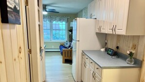 A kitchen with white cabinets, a refrigerator, and a countertop with a vase.