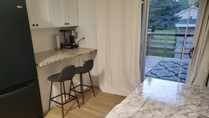 Eine Küche mit Marmorarbeitsplatte, zwei Barhocker, einer Kaffeemaschine und einem Kühlschrank.