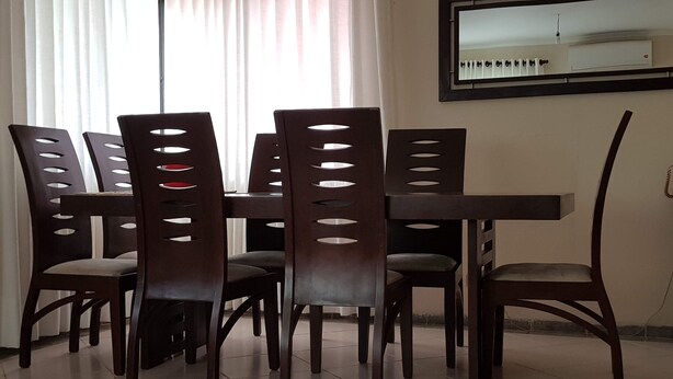 A dining area with a rectangular table and six chairs with cut-out backrests. - Warm house, away from the noise of the city. (Santa Cruz de la Sierra)