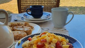 A table set outdoors with a plate of fruit salad, a jug of juice, and a teapot. - Warm house, away from the noise of the city. (Santa Cruz de la Sierra)