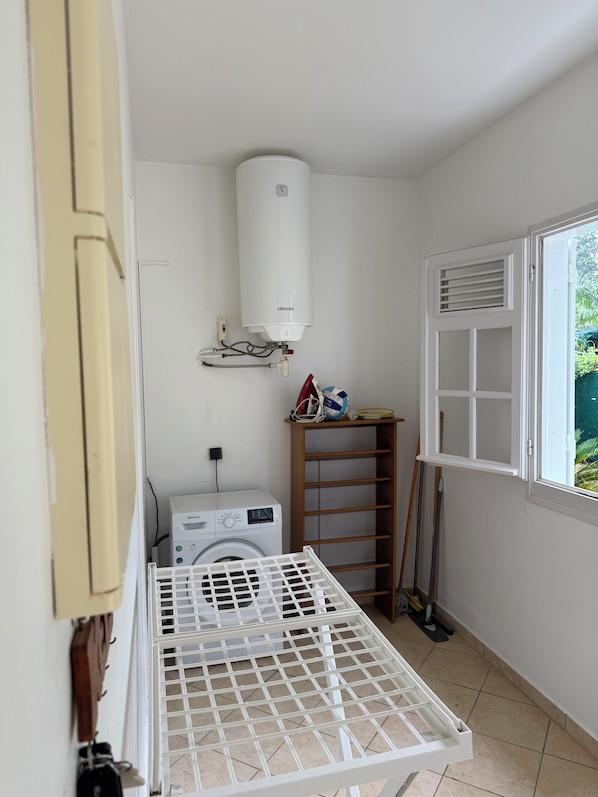 A laundry area with a washing machine, a drying rack, and a water heater.