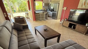A modern living room with a large sectional sofa, a coffee table, and a TV. - Between sun and river: your perfect getaway (Goyave)