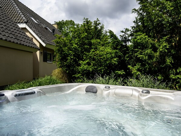 A hot tub in a backyard with a house and trees in the background.