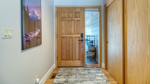 Un couloir avec une porte en bois, un tapis et un tableau encadré accroché au mur.