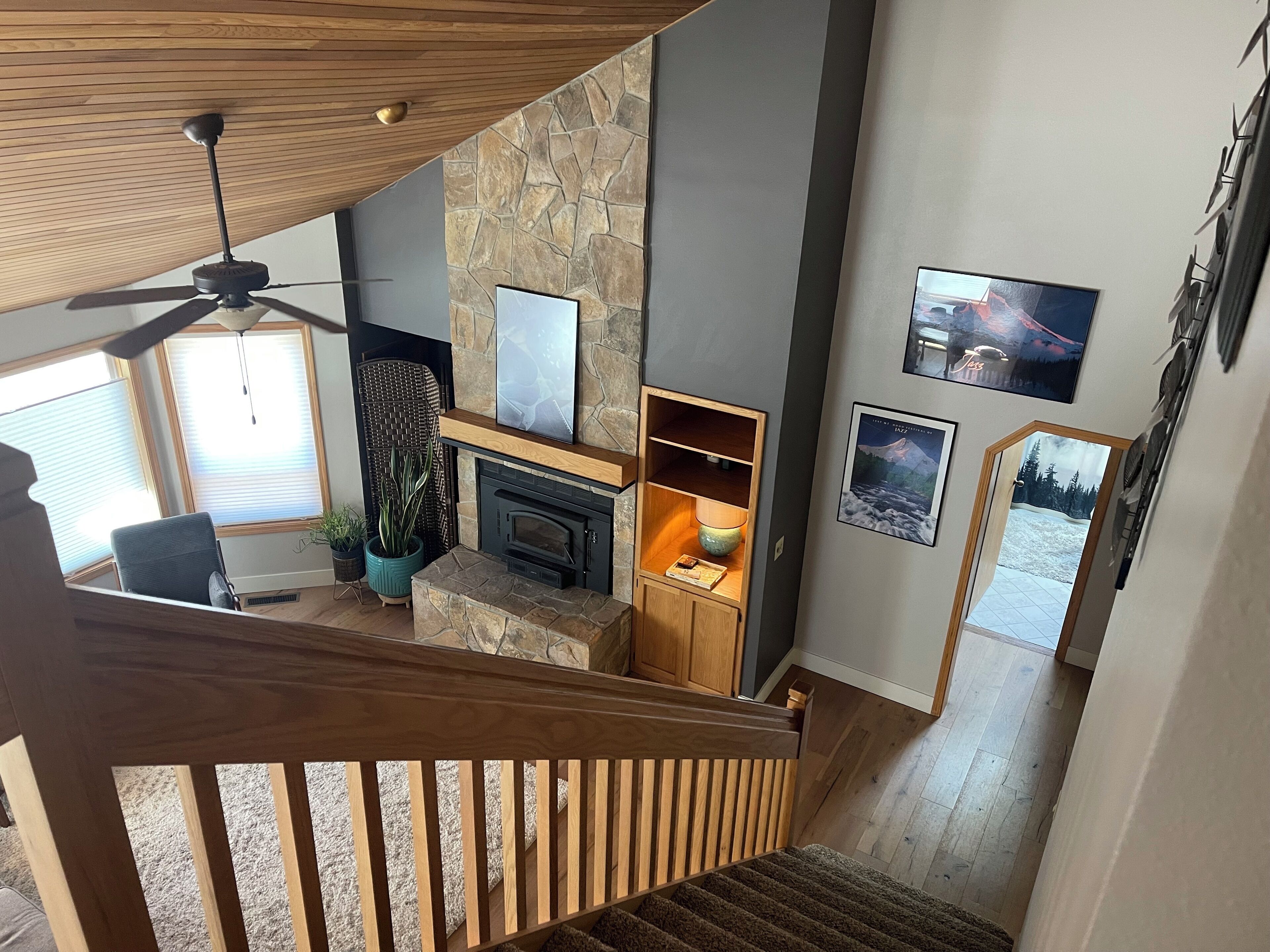 A modern living room with a fireplace, wooden shelving, and a stone accent wall.