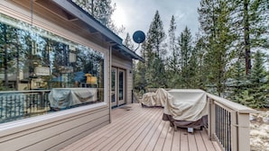 Une terrasse en bois dotée d’un espace salon couvert, d’une antenne parabolique et offrant une vue sur une zone boisée.
