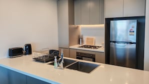 Una cocina moderna con un refrigerador de acero inoxidable, una estufa a gas y un lavamanos con escurreplatos.