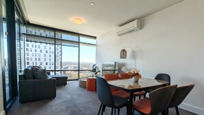Un comedor moderno con una mesa y sillas, un sofá, y un ventanal con vistas a la ciudad.