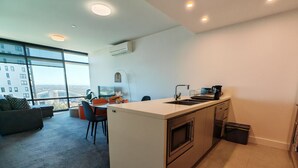 Un apartamento moderno con isla de cocina, comedor y grandes ventanales con vistas a la ciudad.