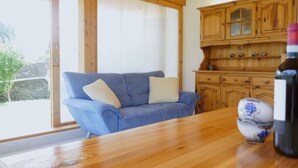 A cozy room with a wooden table, a blue sofa with cushions, and wooden cabinets with glass doors. - Casa Calanca by Interhome (Grono)