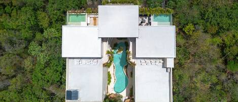 An aerial view of a modern hotel with a central swimming pool surrounded by four wings.
