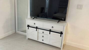 Un mueble blanco de entretenimiento con televisor de pantalla plana, cajones y puerta corredera.