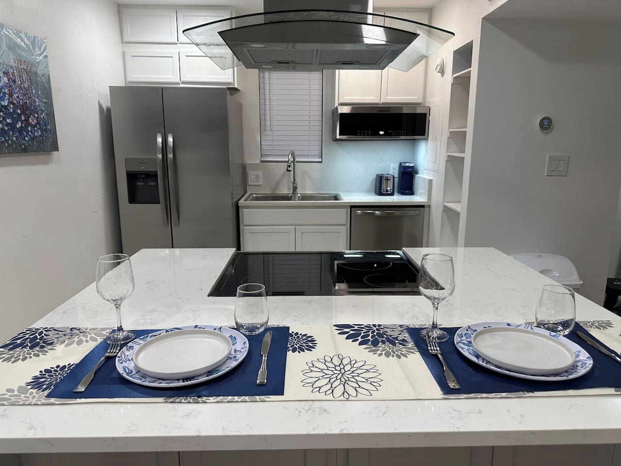Una cocina moderna con una isla central, electrodomésticos de acero inoxidable y una zona de comedor preparada para dos.