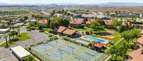 A residential area with a large tennis court, a swimming pool, and surrounding houses.