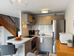 A compact kitchen with a built-in oven, a refrigerator, and a coffee maker.