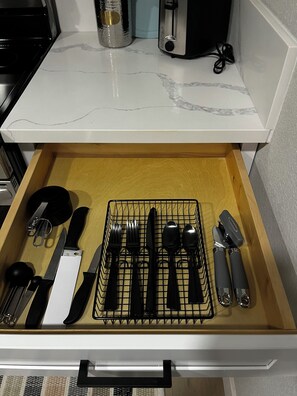 A kitchen drawer with utensils and a toaster.