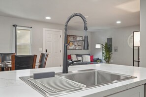 Una cocina moderna con un lavamanos de acero inoxidable, una placa de cocción integrada y un grifo curvo.