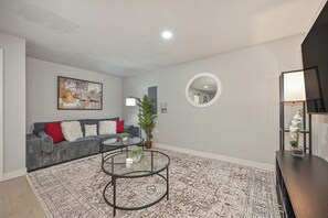 A modern living room with a grey sofa, a round coffee table, and a patterned rug. - Walk to UC Davis Med Center, Modern 2 BR and large office with W/D, WiFi Parking (Sacramento)