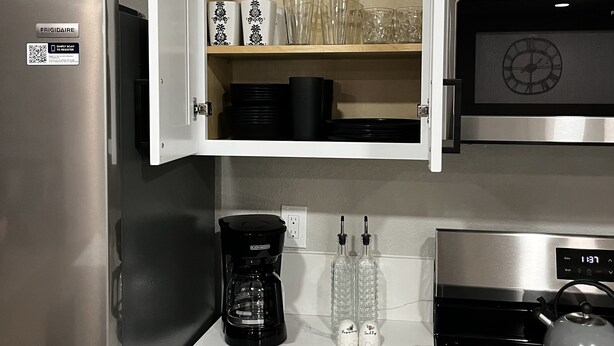 Una cocina con refrigerador empotrado, cafetera, microondas y estufa.