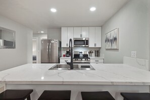 Una cocina moderna con una isla central, electrodomésticos de acero inoxidable y una encimera de mármol.