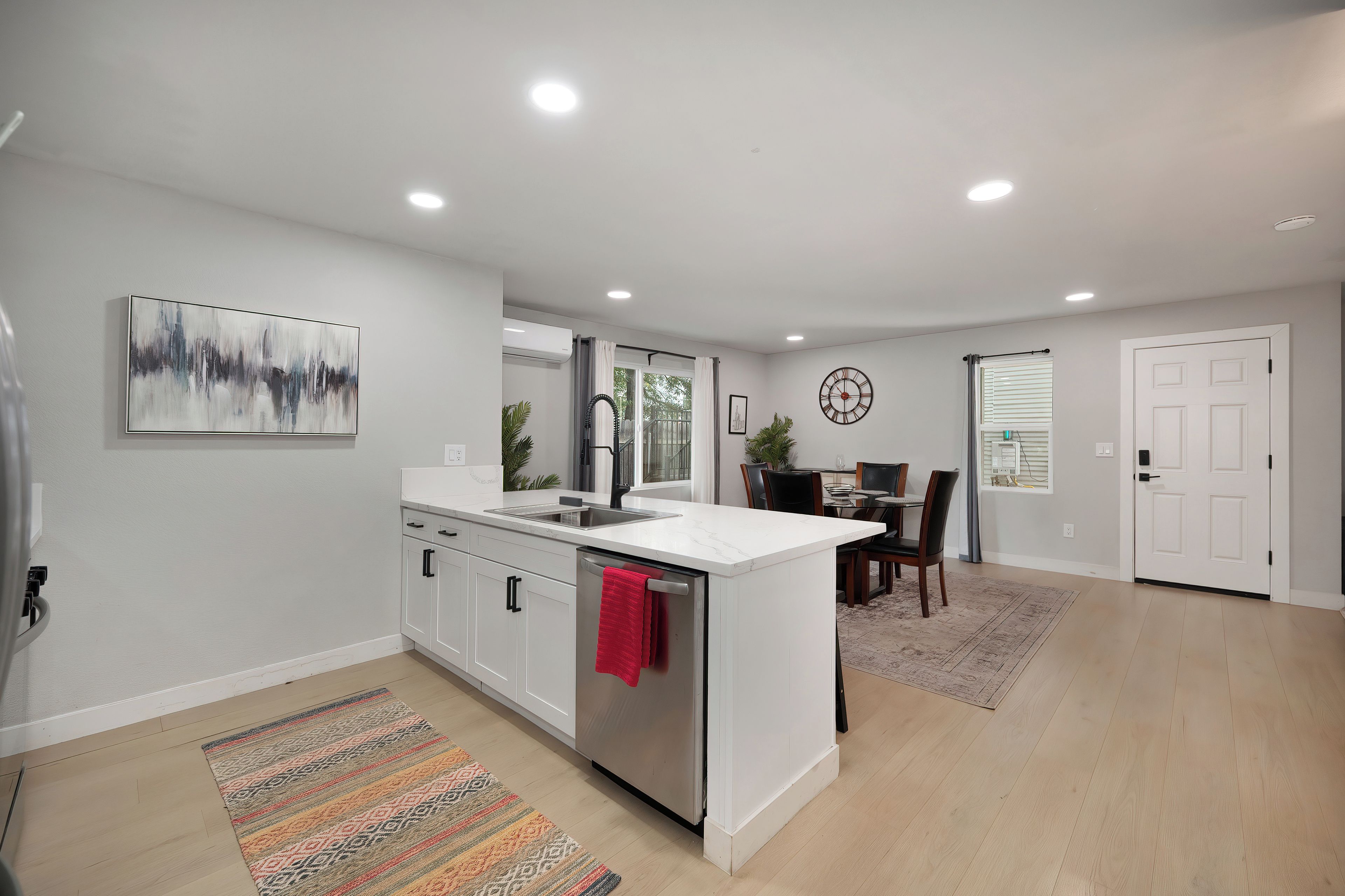 A modern kitchen with white cabinetry, a stainless steel sink, and a red towel.