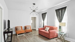 A modern living room with a television, two armchairs, a sofa, and a lamp. - Detroit 3BR Retreat w/ Wi-Fi + Street Parking (Detroit)