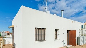 A white building with two windows, a door, and a small staircase leading to a balcony. - San Bernardo ático de 1 dormitorio (Sevilla)