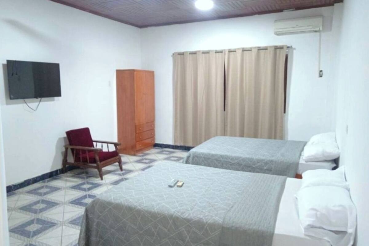 A room with two beds, a TV, a wardrobe, and a chair.